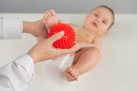 A doctor massages a baby's foot using a spiked ball