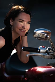 Brunette woman looks in the rearview mirror on a motorcycle. Vertical photo