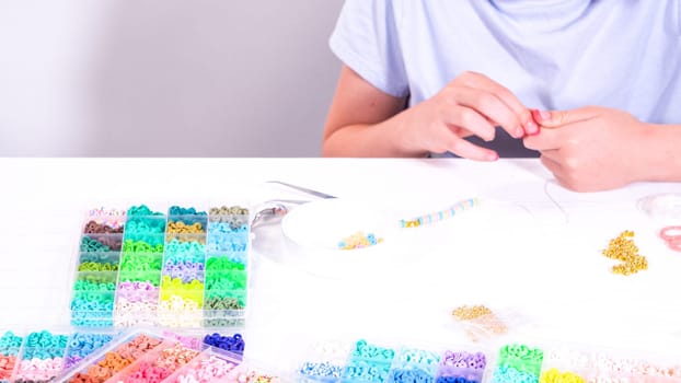 Delicate fingers of a young girl navigate through a treasure trove of bright, multicolored beads, each compartment revealing a new hue to choose from.