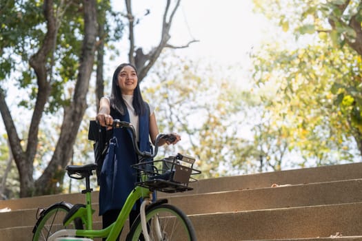 Smiling Asian woman standing outdoors with her bicycle, promoting eco-friendly commuting and a healthy lifestyle