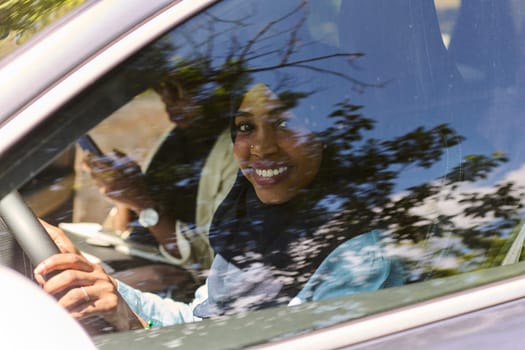 Two Muslim women wearing hijab converse on a smartphone while traveling together in a car through the.