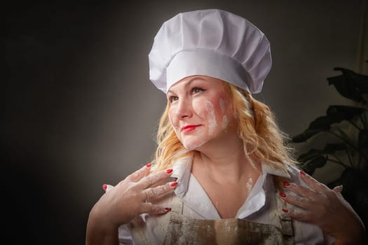 A fat funny female cook in a hat and apron poses in the kitchen and takes selfie. Good cooking and body positive