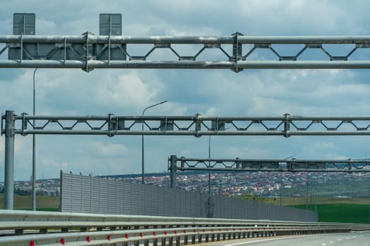 A highway with a lot of traffic lights and a lot of tall metal structures. The sky is cloudy and the city is in the background
