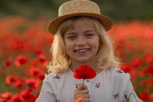 A young girl is holding a red flower in a field of red flowers. She is smiling and looking at the camera