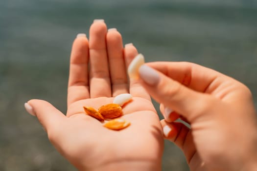 A hand holding a handful of almonds. The almonds are small and round