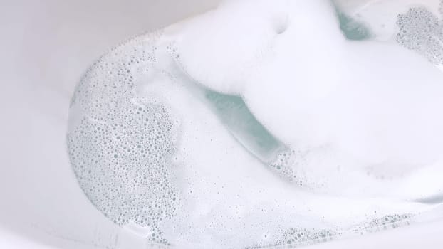 Elegant white bathtub filled with water, featuring a sleek brushed nickel faucet with water flowing gently into the tub. The bathtub’s modern design and the clear, tranquil water suggest a peaceful bathroom setting.