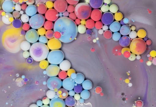 A close-up photograph showcasing a mesmerizing array of colorful bubbles suspended in a liquid medium, creating a stunning abstract composition. The bubbles exhibit a vibrant spectrum of hues.