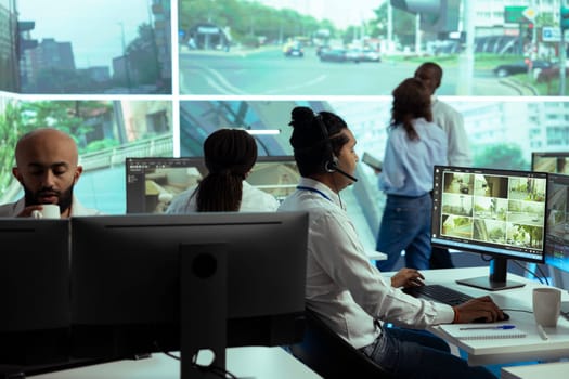 Indian operator following real time traffic footage from CCTV cameras, reporting any irregularities in the urban roads. Male employee monitoring drivers behavior and activity.