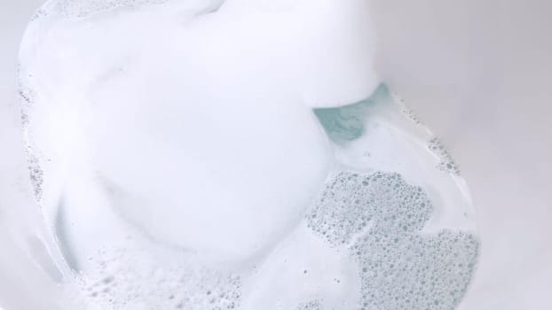 Elegant white bathtub filled with water, featuring a sleek brushed nickel faucet with water flowing gently into the tub. The bathtub’s modern design and the clear, tranquil water suggest a peaceful bathroom setting.