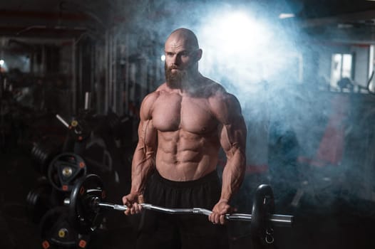 Caucasian bald topless man doing an exercise with a barbell in the gym. Bicep curls with weights