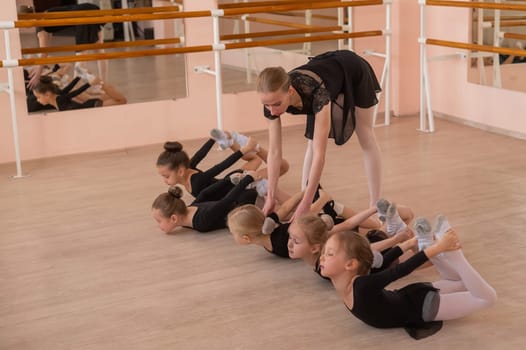 A teacher helps five little girls do a basket exercise