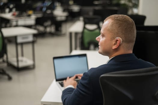 Caucasian deaf man typing on laptop in office