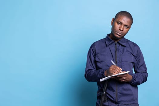 African american bodyguard writing detailed information on his notebook, keeps evidence of all details while he is on protection duty. Male trained agent taking notes to ensure safety.