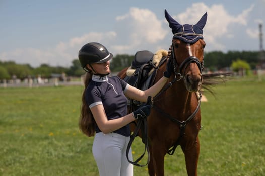 A young girl stands next to a horse before an equestrian competition