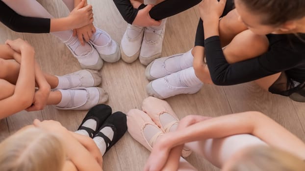 Five little ballerinas and a teacher are sitting in a circle hugging