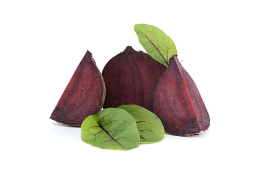 Slices of beetroot revealing their vibrant purple interiors complete with their fresh green leaves set against white background