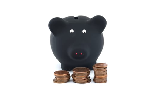 Black piggy bank is flanked by three separate stacks of coins, each stack decreasing in size from left to right, all set against a stark white background