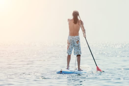 Man Sea Sup. Strong athletic man learns to paddle sup standing on board in open sea ocean on sunny day. Summer holiday vacation and travel concept. Aerial view. Slow motion.