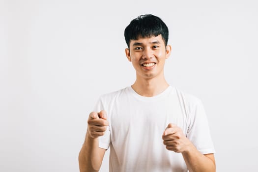 Portrait of a happy young man smiling while playfully pointing two fingers at the camera. Isolated on white background, he radiates optimism and a friendly demeanor.