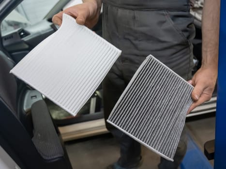 Mechanic holding old and new cabin air car filters
