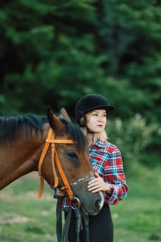 Happy blonde with horse in forest. Woman and a horse walking through the field during the day. Dressed in a plaid shirt and black leggings