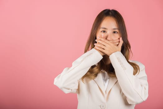 Asian happy portrait beautiful young woman standing smiling surprised excited her covering mouth with hands see only eyes and looking to camera on pink background with copy space for text