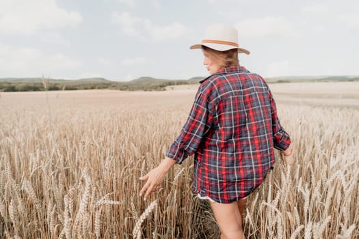 Woman farmer walks through a wheat field at sunset, touching green ears of wheat with his hands. Hand farmer is touching ears of wheat on field in sun, inspecting her harvest. Agricultural business.