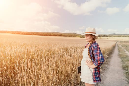 Woman farmer walks through a wheat field at sunset, touching green ears of wheat with his hands. Hand farmer is touching ears of wheat on field in sun, inspecting her harvest. Agricultural business.