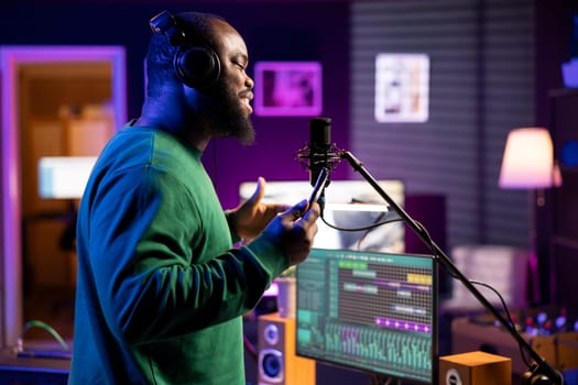 Young performer singer does a recording session for his acoustic song, performing the acapella version on microphone in home studio. Confident songwriter working on new soundtracks for an album.