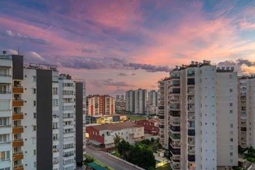 Antalya cityscape at sunset with apartment buildings in the foreground and mountains in the background