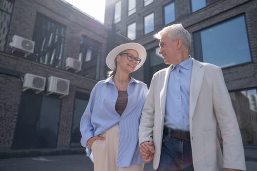 An elderly couple in love walks through the city