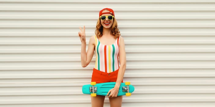 Summer portrait of happy cheerful stylish young woman with skateboard in colorful clothes posing on white background