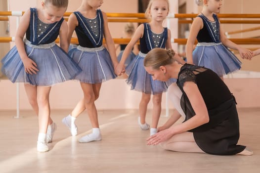 Children's ballet school. Caucasian woman teaching ballet to little girls