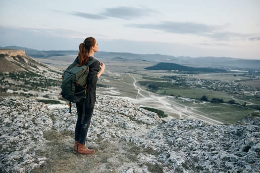 adventurous woman with backpack admiring stunning valley view from mountain peak