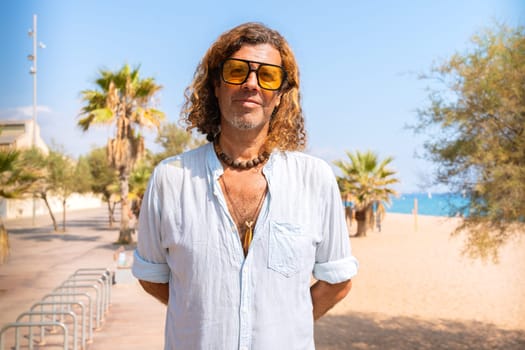 Caucasian adult man wearing smiling sunglasses looking at camera. Man on vacation on the coast.