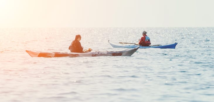 Happy smiling woman in kayak on ocean, paddling with wooden oar. Calm sea water and horizon in background