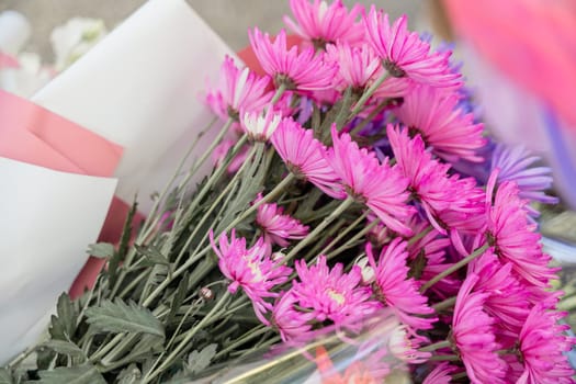 A bouquet of pink flowers sits on a table. The flowers are arranged in a way that makes them look like they are in a vase