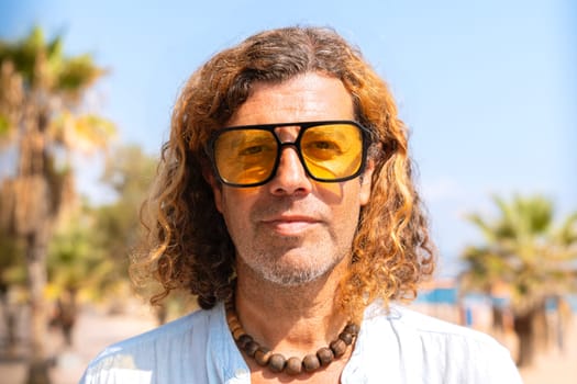 Caucasian adult man wearing smiling sunglasses looking at camera. Man on vacation on the coast.