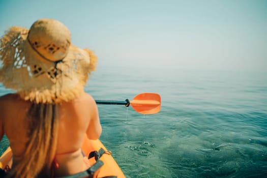 Woman in kayak back view. Happy woman with long hair in a swimsuit and hat floating in kayak on the sea. Summer holiday vacation. Summer holidays vacation at sea