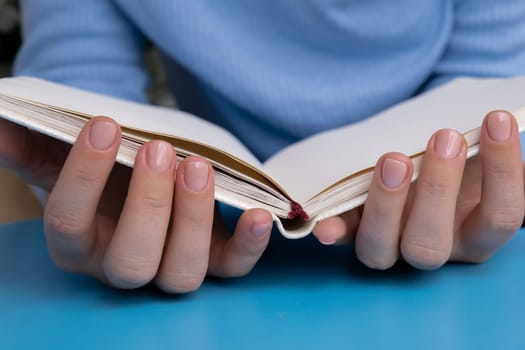 Pastel softness manicured nails with paper notebook on blue background. Woman showing her new manicure in colors of pastel palette. Simplicity decor fresh spring vibes earth-colored neutral tones design