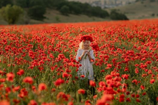 A young girl stands in a field of red poppies. The field is full of flowers and the girl is wearing a red headband