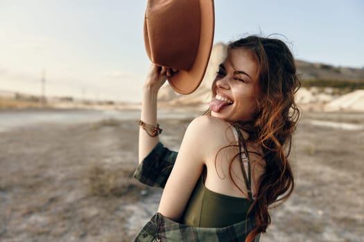 Playful woman in desert tongue out, hat on head