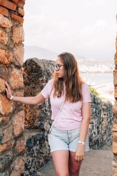 Woman at Fortress ruins of the historical Red Tower - Kizil Kule, in Alanya Castle. The Red Tower is the symbol of the Alanya city, and the famous touristic place, Turkey (Turkiye).