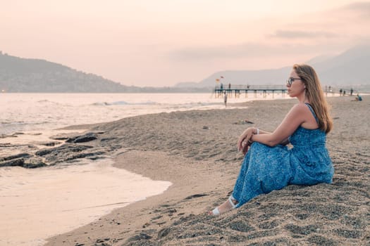 Woman sits on the beach and looks at the sea in Alanya city, Turkey. Travelling or vacation concept