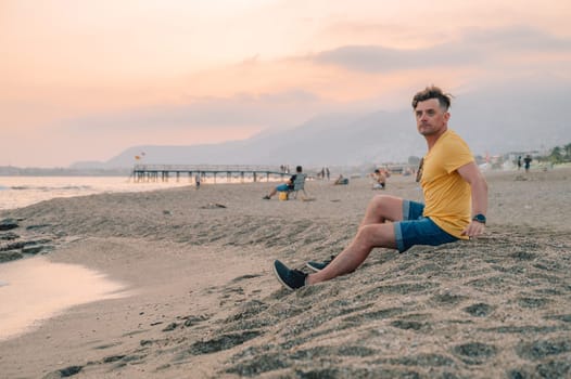 Man sits on the beach and looks at the sea in Alanya city, Turkey. Travelling or vacation concept