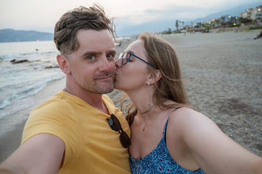 Happy couple taking a photo on a beach at the sea in Alanya city, Turkey. Travelling or vacation concept