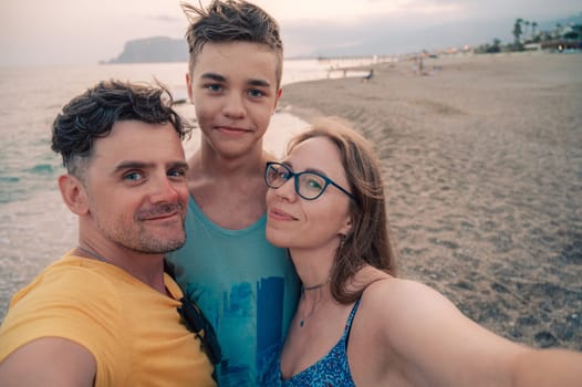 Happy family taking a photo on a beach at the sea in Alanya city, Turkey. Travelling or vacation concept