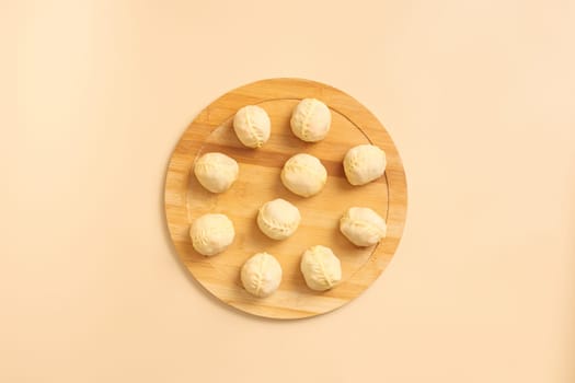 Top view of traditional Central Asian manty arranged on a round wooden board.