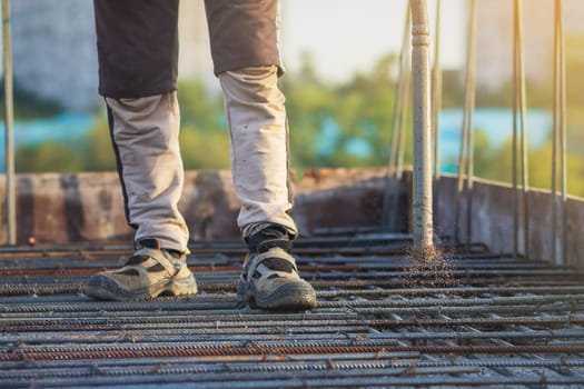 A construction worker employs a concrete vibrator to compact the concrete at a construction site, ensuring proper consolidation.