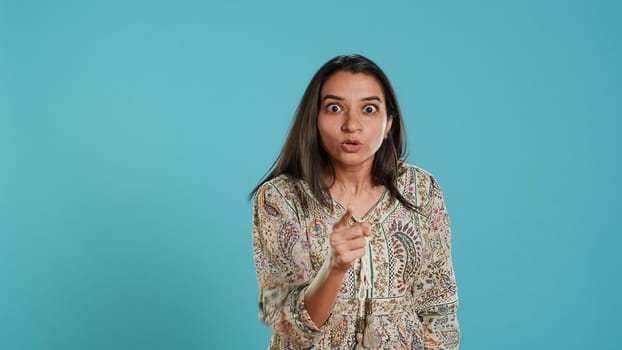 Upset indian person fighting with friend, doing scolding gesturing, isolated over studio backdrop. Annoyed woman arguing with opponent during discussion, doing admonishing hand gestures, camera A